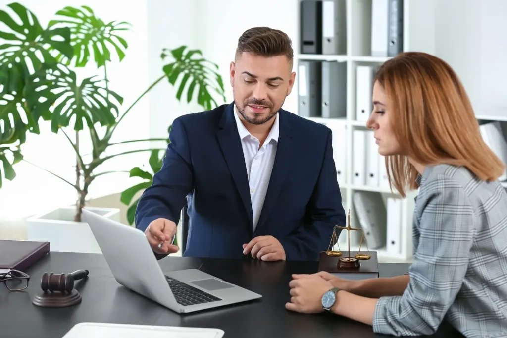 An attorney and client interacting with a laptop.